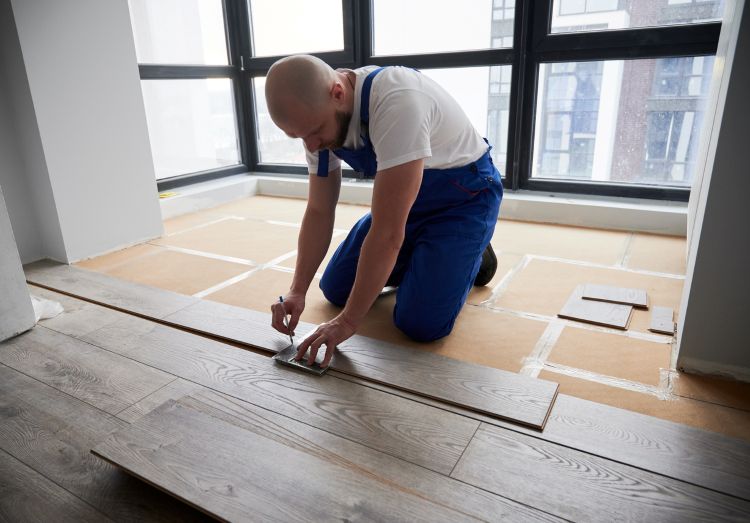 Man installing prefinished hardwood flooring in a room