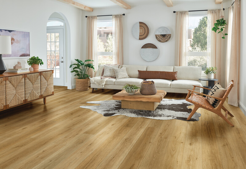 Wide plank solid hardwood flooring in a living room with a couch and large windows on each side